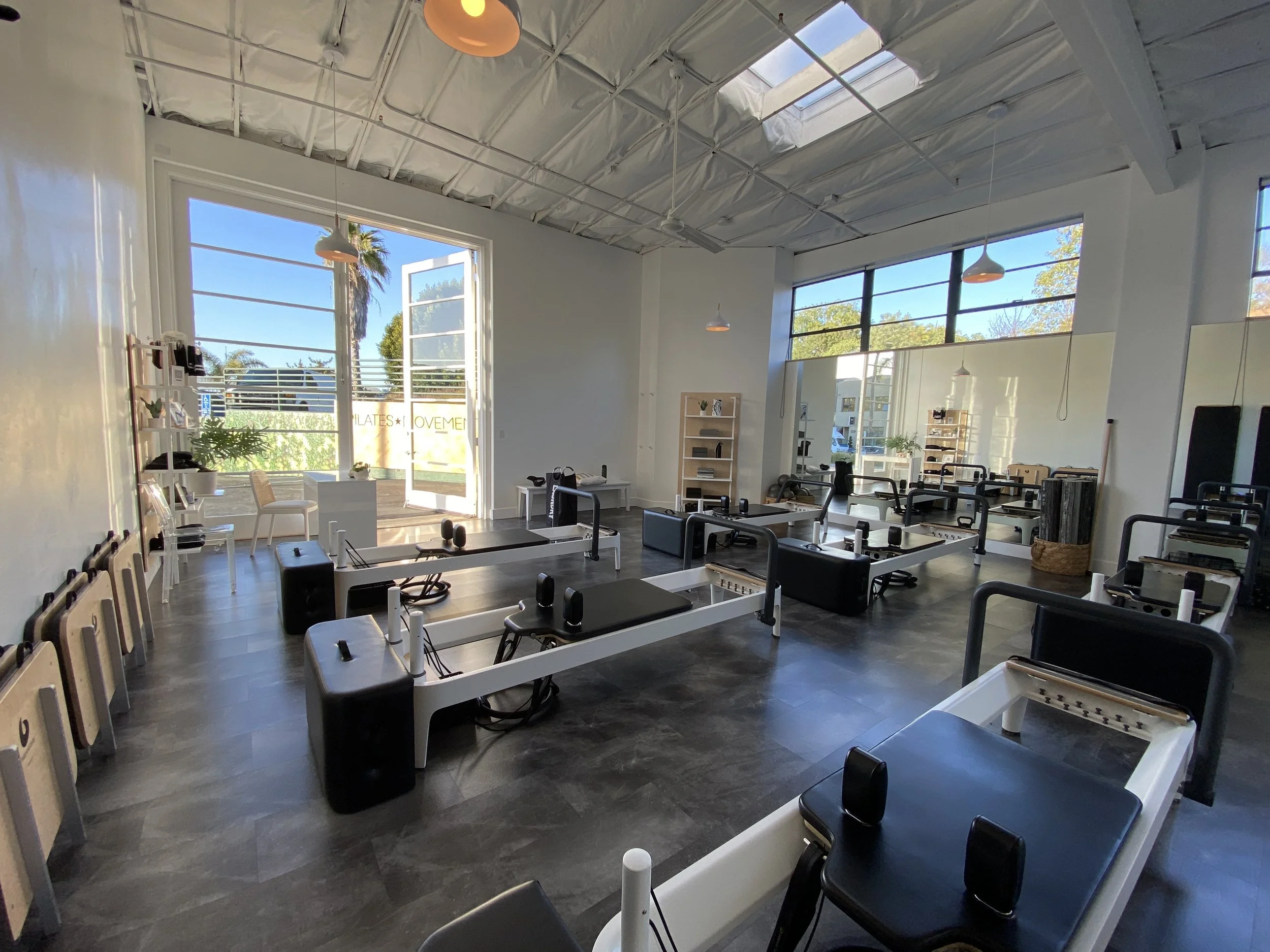 Sunlit Core & Co. studio with reformers under a high ceiling